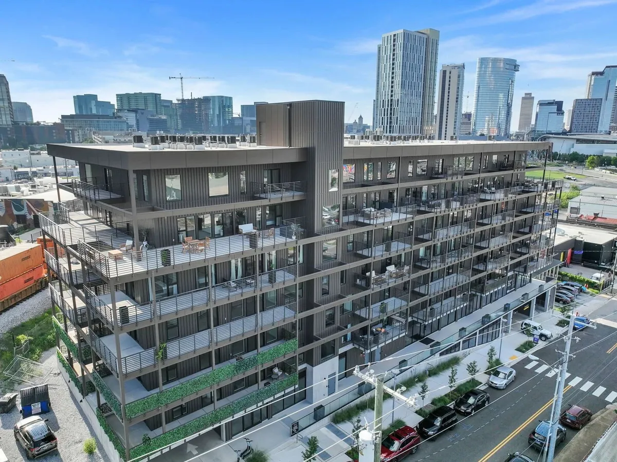 A striking exterior view of a modern apartment building with rooftop spaces and the surrounding cityscape. The scene hints at the possibility of urban adventure, rooftop gatherings, and connection to Nashville’s skyline.