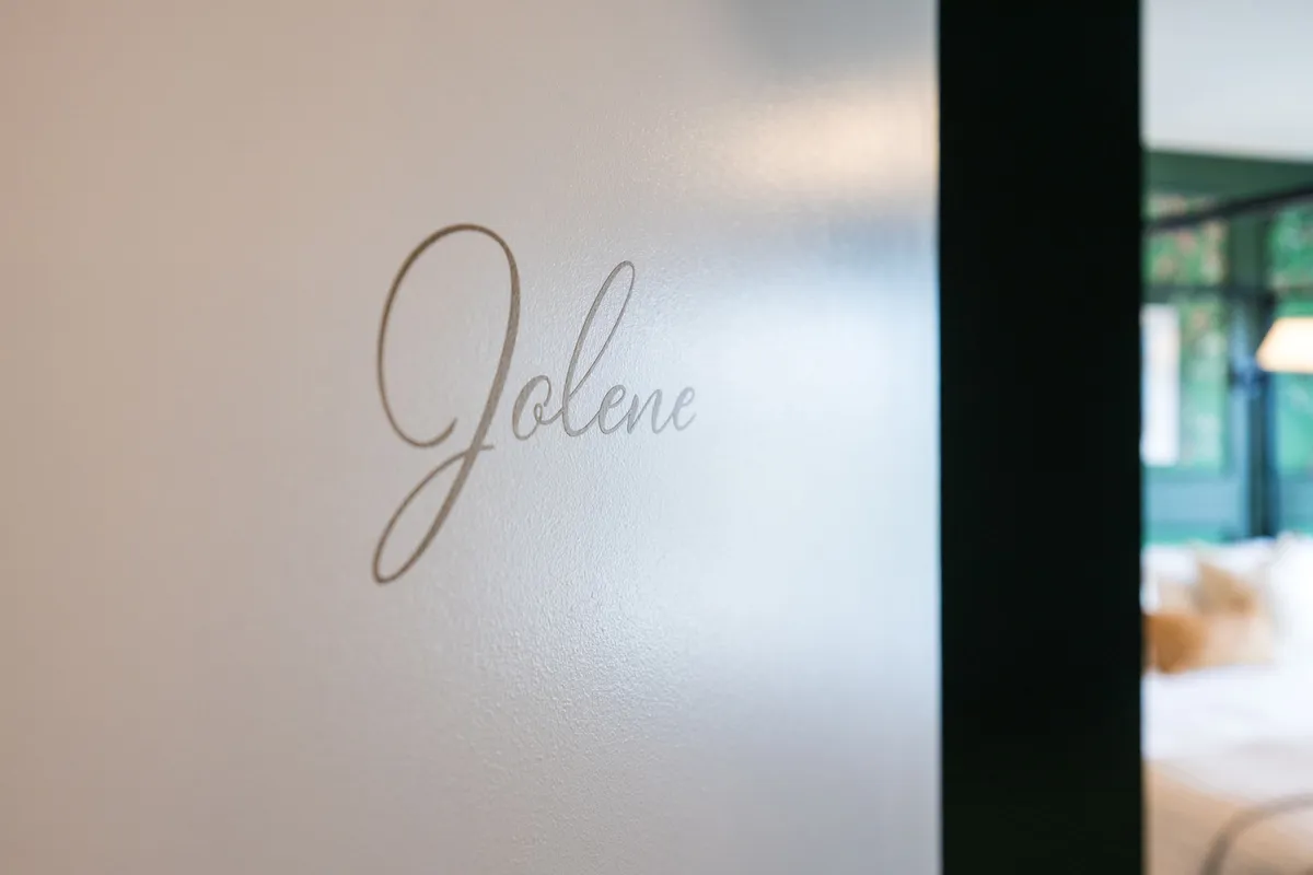 This image shows the name 'Jolene' elegantly displayed on the wall of a serene bedroom. The décor is personal and theme-driven, creating a sense of intimacy and distinctive style, clearly referencing Dolly’s iconic hit and the themed primary suite discussed in the section.