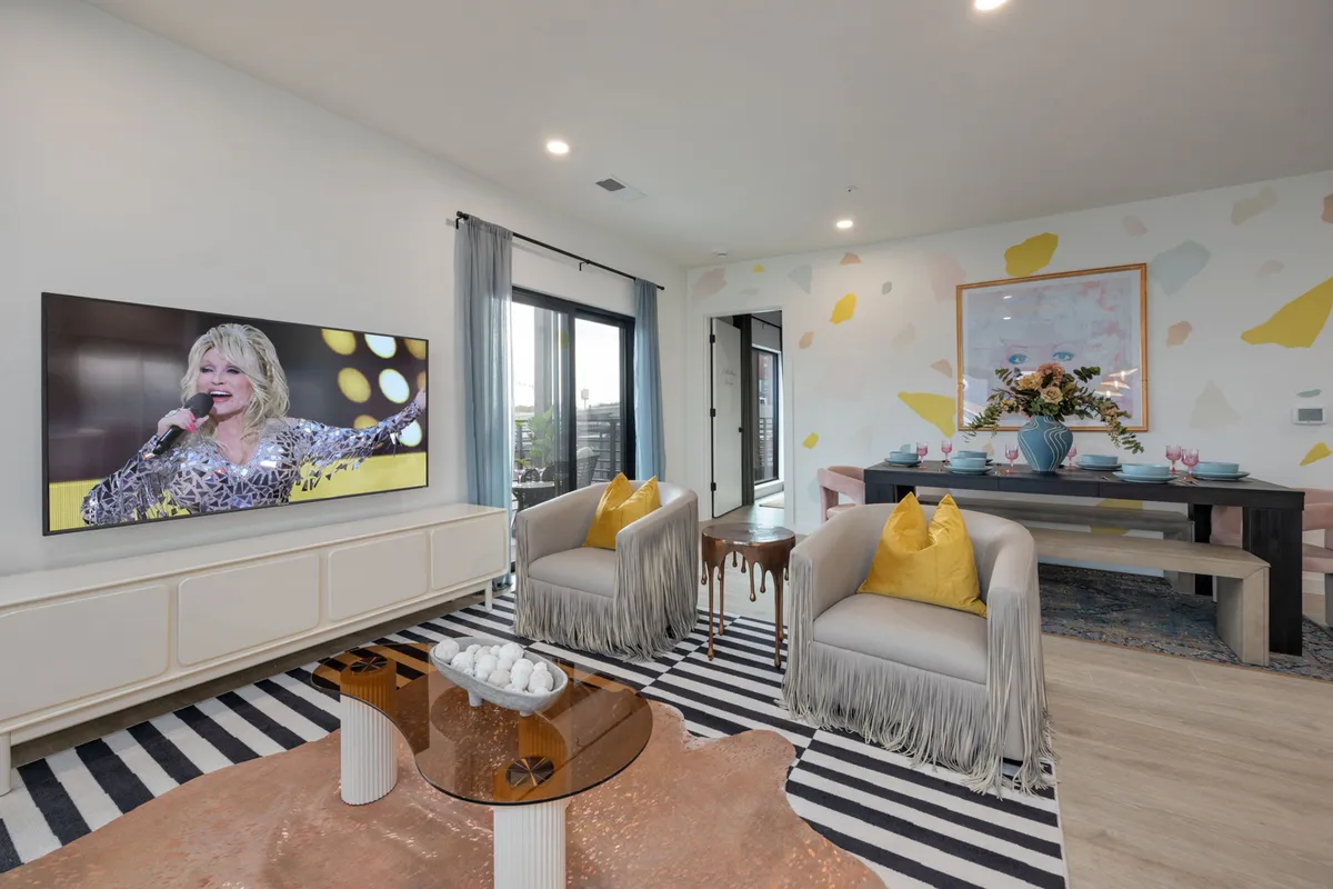A lively living room with a large television displaying a performance, a colorful accent wall, and a stylish seating arrangement, inviting guests to gather for movie nights or group entertainment.