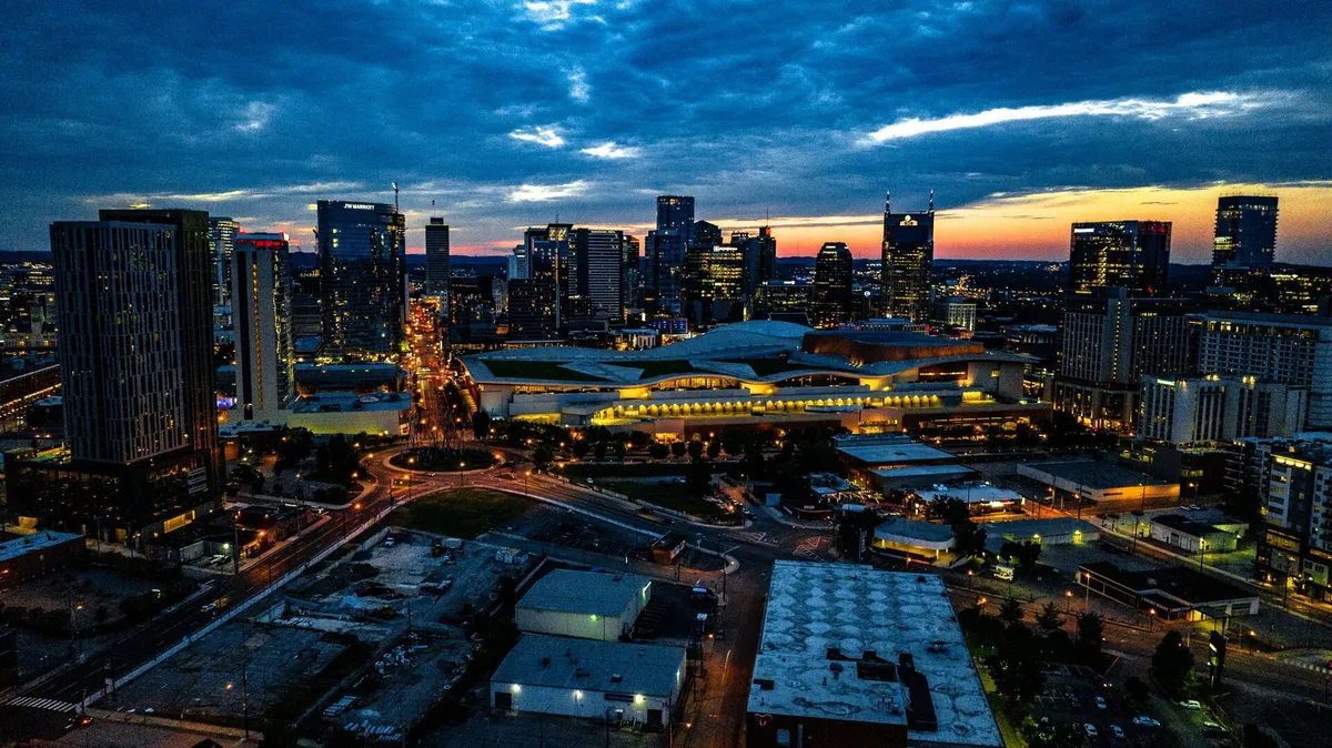 A vibrant nighttime city skyline illuminated by building lights, with visible roadways and an energetic urban atmosphere. The image evokes the excitement of city nightlife, dining, and event-going, placing the viewer right where the action happens.